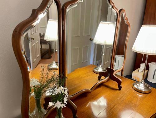 a mirror on a table with two lamps on it at Rowan Brae Historic Guesthouse in Blackheath
