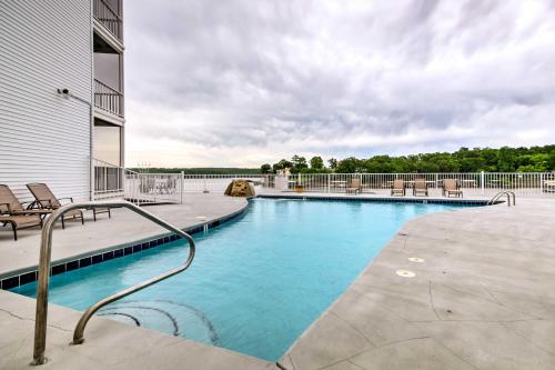 a swimming pool with chairs and a building at Lakefront Osage Beach Condo Dock Your Boat Here! in Osage Beach