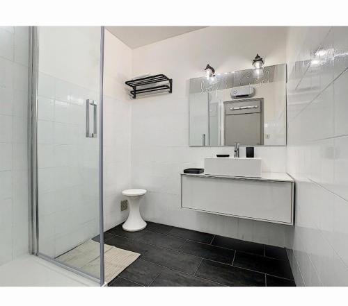 ein weißes Bad mit einem Waschbecken und einer Dusche in der Unterkunft Aile de villa climatisée avec piscine in Porticcio