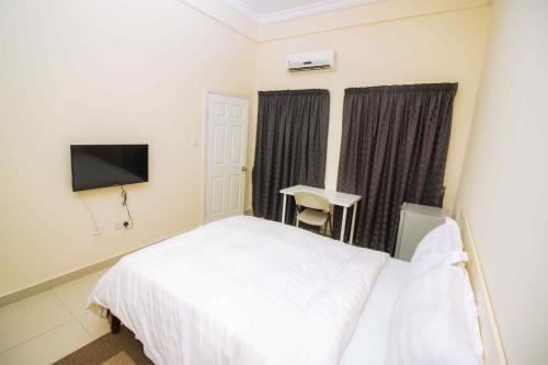 a bedroom with a white bed and a television at Brown Hills Residences in Aburi