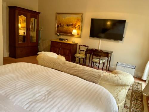 a bedroom with a bed and a flat screen tv at Rowan Brae Historic Guesthouse in Blackheath
