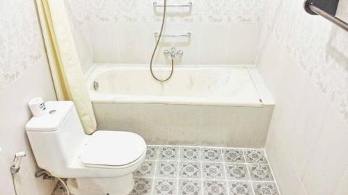 a bathroom with a toilet and a tub and a sink at Masainn Hotel Kuta in Kuta