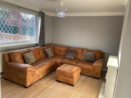 a brown leather couch in a living room with a window at Ideal Abode Greenfields in Chester