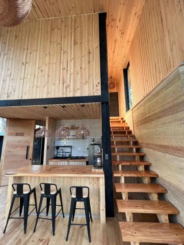 a room with a staircase and some stools at Tripanko Lodge & Bungalows in Pichilemu