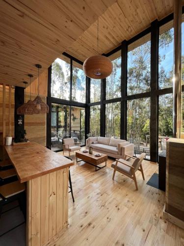 a living room with wooden floors and large windows at Tripanko Lodge & Bungalows in Pichilemu