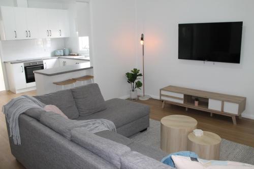 uma sala de estar com um sofá cinzento e uma cozinha em The Renmarkable Cottage em Renmark