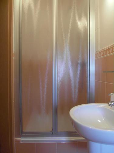 a shower with a glass door next to a sink at Penzión Admit in Terchová