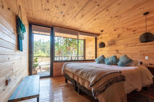 a bedroom with a bed and a wooden wall at Tripanko Lodge & Bungalows in Pichilemu