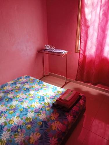 a small bedroom with a bed with a colorful blanket at HOMESTAY CAHAYA PUTERI in Tangga Batu