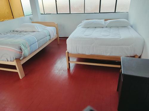 duas camas sentadas uma ao lado da outra num quarto em ENEDE HOSTEL em Cusco