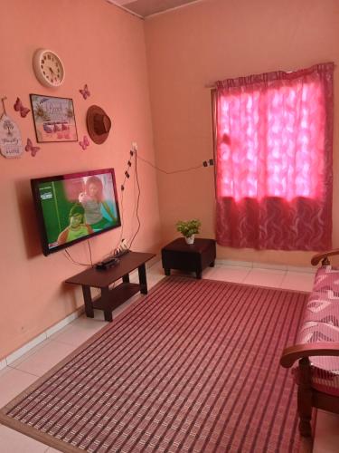 a living room with a tv and a red curtain at HOMESTAY CAHAYA PUTERI in Tangga Batu