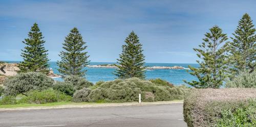a road with trees and the ocean in the background at Stoneferry- A Beachfront Beauty - Free Wifi in Port Elliot