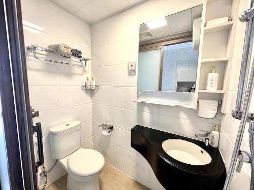 a white bathroom with a toilet and a sink at DayInn, Skyhouse BSD Lux and Homey Studio, near AEON BSD and ICE BSD in Cilenggang