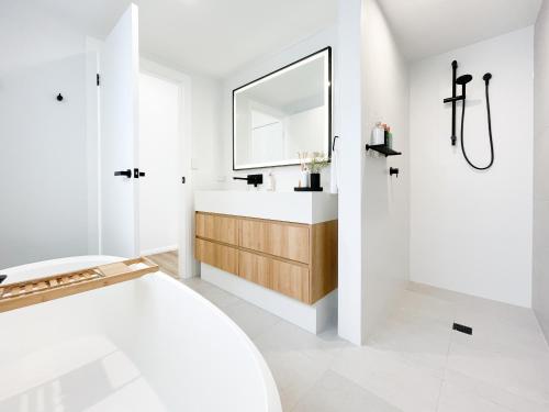 uma casa de banho branca com um lavatório e um espelho em MySpace on Market - Apartment 2 em Mudgee