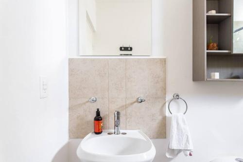 een badkamer met een witte wastafel en een spiegel bij Lovely COZY Apt w/pool 2 Bedrooms. Great location! in Puerto Morelos