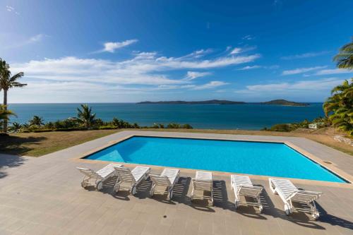 un grupo de sillas y una piscina con el océano en Villa Vanua - Private Luxury Villa, en Rakiraki