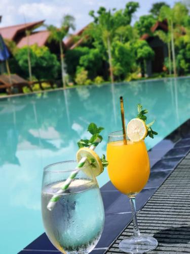 two drinks on a table next to a swimming pool at Anukama Resort in Nilaveli