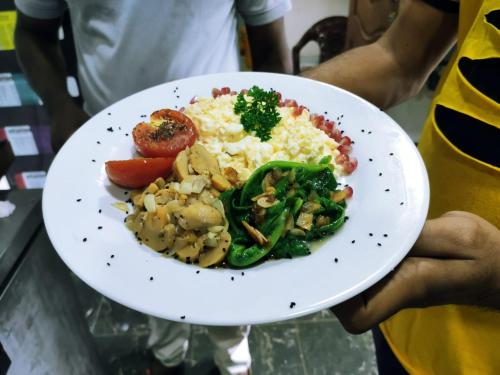 a person holding a white plate of food at Anukama Resort in Nilaveli
