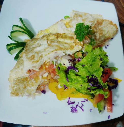 a white plate with a piece of food and a salad at Anukama Resort in Nilaveli