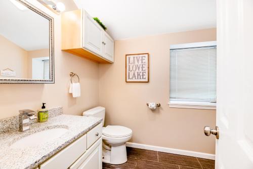 a bathroom with a toilet and a sink and a mirror at Live Laugh Lake in Rushville