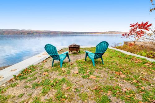 two blue chairs sitting next to a table next to a lake at Live Laugh Lake in Rushville