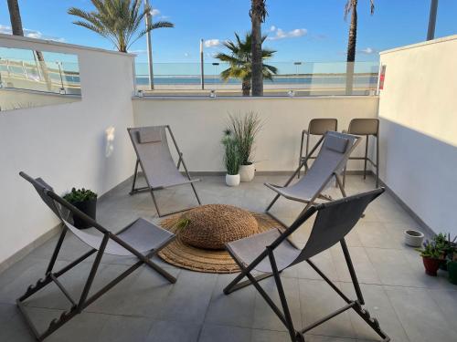 a group of chairs sitting on a patio with the beach at Arenas de Sanlúcar in Sanlúcar de Barrameda