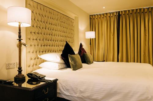 a hotel room with a bed with a phone on it at The Keadeen Hotel in Newbridge