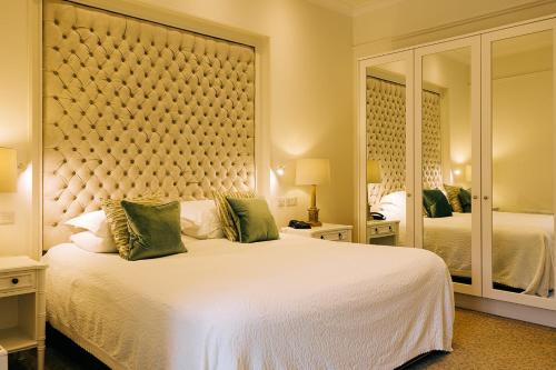 a bedroom with a large white bed and a large mirror at The Keadeen Hotel in Newbridge