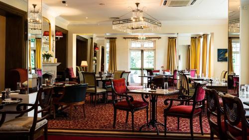 a restaurant with tables and chairs and a chandelier at The Keadeen Hotel in Newbridge
