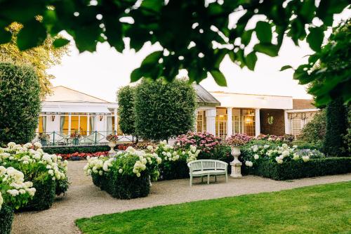 a garden with a bench and flowers in front of a house at The Keadeen Hotel in Newbridge