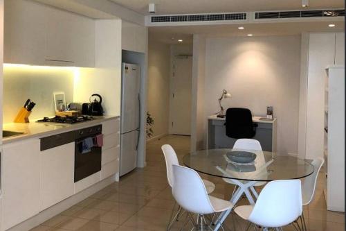 a kitchen with a glass table and white chairs at Darwin Waterfront Short Stay Apartments in Darwin