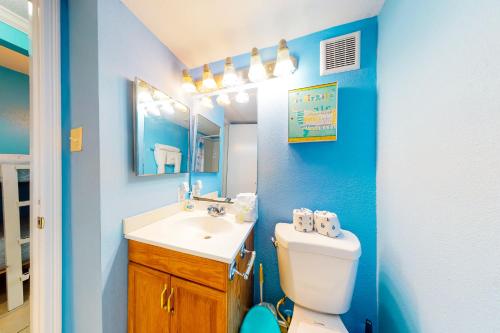 a bathroom with a toilet and a sink and a mirror at Victorian Condos Barefoot Beach Haven in Galveston