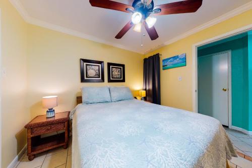 a bedroom with a bed and a ceiling fan at Victorian Condos Barefoot Beach Haven in Galveston