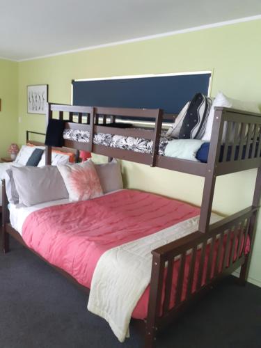 um quarto com 2 beliches e lençóis cor-de-rosa em Quail's Nest em Mangawhai