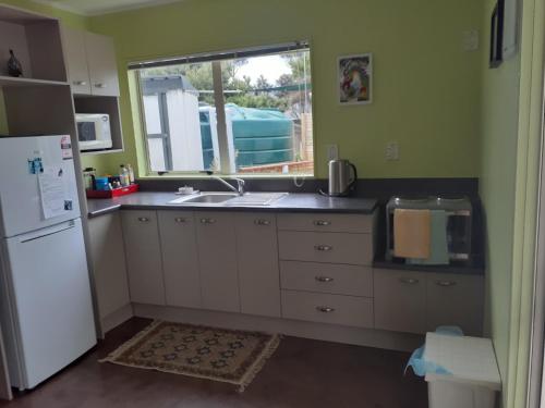 uma cozinha com um lavatório, um frigorífico e uma janela em Quail's Nest em Mangawhai