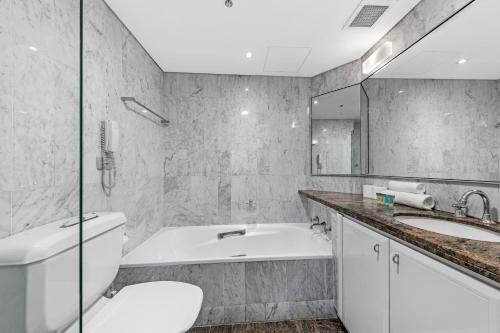y baño con bañera, aseo y lavamanos. en Comfy One Bedroom Apartment In Heart of The Rocks, en Sídney