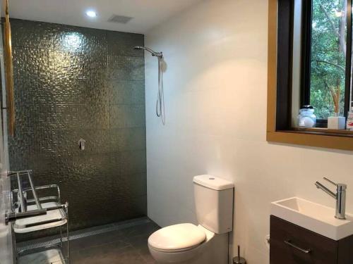 a bathroom with a shower and a toilet and a sink at Golden Retreat Ultimate 5 Bed - Villa & Guesthouse in Uki
