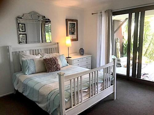 a bedroom with a white bed and a mirror at Golden Retreat Ultimate 5 Bed - Villa & Guesthouse in Uki