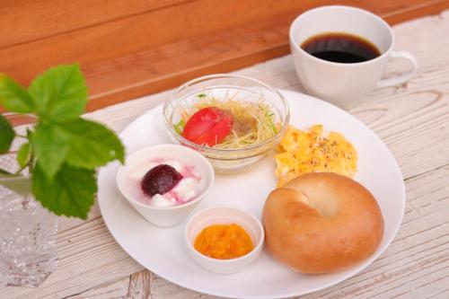 un plato de comida con un bagel y una taza de café en House Hotel Amami Minpaku Mura & Sauna, en Amami