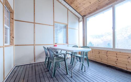 a table and chairs in a room with windows at Rest Pension in Pyeongchang