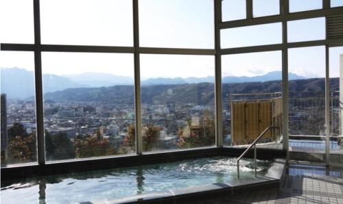 a large swimming pool in a building with windows at Natural Farm City Noen Hotel in Chichibu