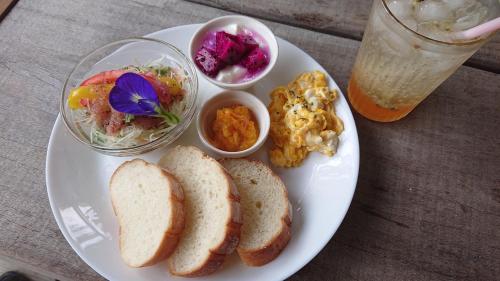 a plate of food with bread and a salad and a drink at House Hotel Amami Minpaku Mura & Sauna in Amami