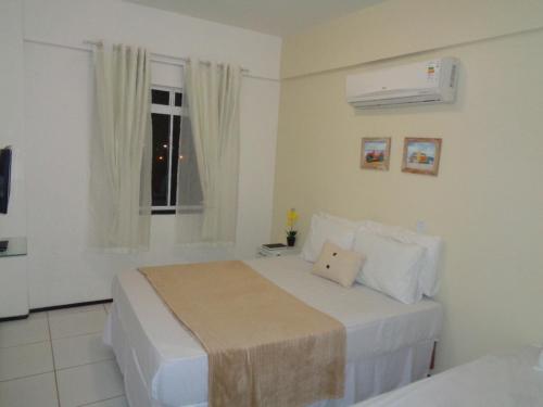 Habitación blanca con cama y ventana en Brisa Brasil Residence, en Fortaleza
