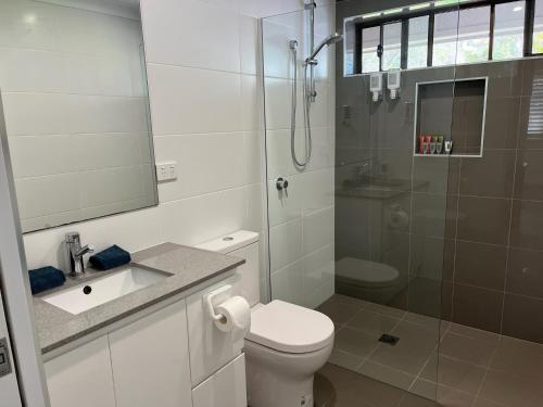 a white bathroom with a toilet and a shower at Emina's Granny Flat in Woollamia