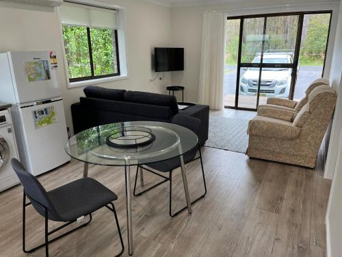 ein Wohnzimmer mit einem Glastisch und einem Sofa in der Unterkunft Emina's Granny Flat in Woollamia