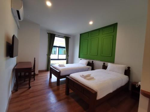 two beds in a room with a green headboard at โรงแรมรชาโขง Racha Khong Hotel in Nakhon Phanom