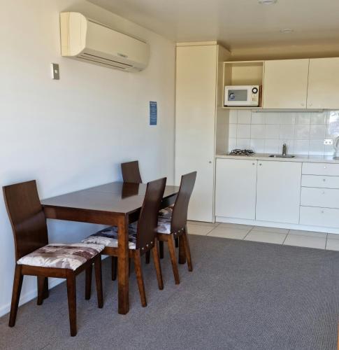 a dining room with a table and chairs and a kitchen at Methven Motel & Apartments in Methven