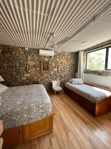 a bedroom with two beds and a stone wall at Cabañas Caballieri in Pisco Elqui