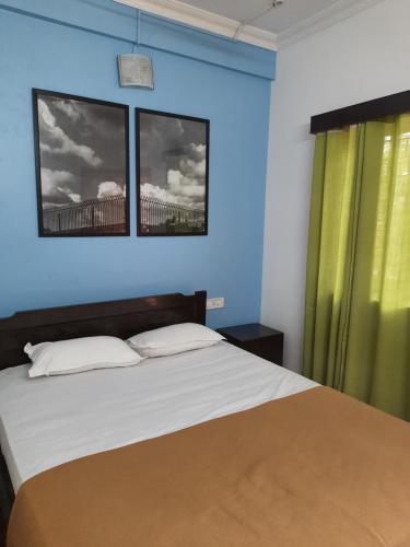 1 dormitorio con 1 cama con paredes azules y 2 ventanas en Cherry blossom guest house en Arpora