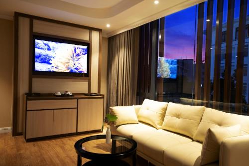 a living room with a white couch and a large window at Millennium Hue Hotel in Hue